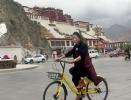 May 16,2017--Jamyang Tso, a resident of Lhasa, rides an Ofo bike on Monday near the Potala Palace. [Photo by Palden Nyima/China Daily] 