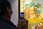 April 4, 2018 -- People take photos of Thangka paintings. (Photo by Zhou Wenyuan)