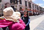 June 24, 2019 -- A tourist poses for photos on a street in Lhasa, capital city of southwest China`s Tibet Autonomous Region, June 20, 2019. Lhasa has entered its peak season for tourism with delightful weather and enchanting scenery. (Xinhua/Jigme Dorje)