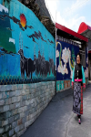 June 13,2020 -- A Qiang woman walks past a wall painted with images themed on Qiang ethnic culture, in Jiashan village, Lixian county, Aba Tibetan and Qiang autonomous prefecture, Southwest China`s Sichuan province. [Photo provided to chinadaily.com.cn]
