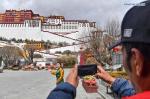 Dec.31,2020 -- A tour guide (L) speaks during a livestreaming tour in the Potala Palace, a UNESCO world heritage site, in Lhasa, southwest China`s Tibet Autonomous Region, March 1, 2020. Today, 5,417 villages, or 99 percent of all villages in the region, have 4G network coverage, and 5,439 villages have fiber-optic network connections. Aided by broadband and 4G coverage, mobile Internet is transforming the way of life on the plateau. E-commerce is booming, generating new avenues of income for Tibetans. (Xinhua/Jigme Dorje)