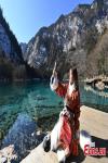 A tourist wearing ethnic costumes takes selfies at Jiuzhaigou National Park in the Aba Tibetan and Qiang Autonomous Prefecture, southwest China`s Sichuan Province, Jan. 5, 2022. (Photo by An Yuan)