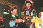 Drolkar (right), a resident of Gape, a village in Shigatse, Tibet autonomous region, offers homemade barley wine to her sister-in-law Phurbu on Thursday, which was Losar, or Tibetan New Year. LHAMO/FOR CHINA DAILY
