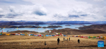 This photo taken with a mobile phone shows tourists enjoying scenic beauty of the Yamzbog Yumco Lake, southwest China`s Tibet Autonomous Region, May 1, 2023. (Xinhua/Shen Hongbing)