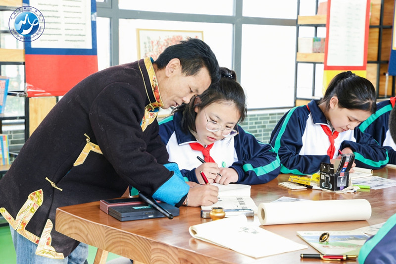 A teacher helps a student during a traditional ethnic Tibetan writing script class at Beijing Experimental High School. [Photo provided to China Daily]