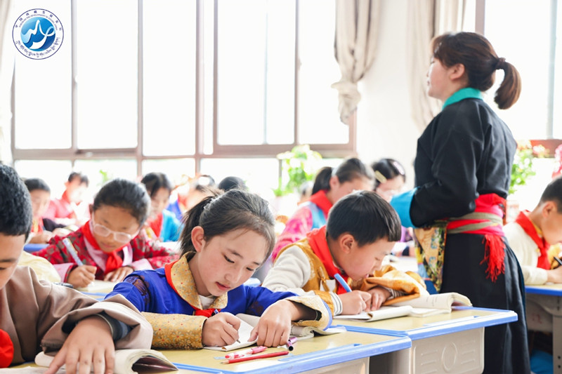 Students write under the supervision of their teacher during a lesson at Nyingchi No 2 Primary School in May. [Photo provided to China Daily]