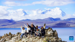 Tourists pose for photos by the Puma Yumco Lake in Nagarze County of Shannan, southwest China`s Tibet Autonomous Region, July 4, 2023. (Xinhua/Chen Shangcai)