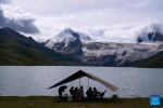 Tourists enjoy the lake scenery at the foot of the Sapukonglagabo Mountain in Biru County of Nagqu, southwest China`s Tibet Autonomous Region, Aug. 16, 2023. (Xinhua/Jiang Fan)