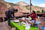 A villager promotes salt produced by her family to a tourist near a salt field in Naxi Ethnic Township of Markam County in the city of Qamdo, southwest China`s Tibet Autonomous Region, Oct. 20, 2023. (Xinhua/Sun Fei)