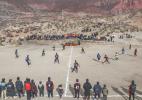 Players participate in a soccer game while other villagers watch on Jan 21. SUN FEI/XINHUA