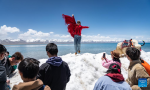 A tourist poses for photos by the Lake Namtso in southwest China`s Xizang Autonomous Region, May 19, 2024. As temperature rises and ice melts, the Lake Namtso will enter its tourism season. (Xinhua/Tenzin Nyida)