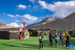 Tourists walk in a base camp of Mount Qomolangma in southwest China`s Xizang Autonomous Region, May 24, 2024. The Mount Qomolangma National Park has entered peak tourism season. From Jan. 1 to May 20 this year, the Mount Qomolangma scenic spot has received about 136,000 tourists. (Xinhua/Sun Fei)