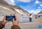 A tourist poses for photos with the monument to the elevation survey of Mount Qomolangma in southwest China`s Xizang Autonomous Region, May 24, 2024. The Mount Qomolangma National Park has entered peak tourism season. From Jan. 1 to May 20 this year, the Mount Qomolangma scenic spot has received about 136,000 tourists. (Xinhua/Sun Fei)