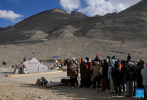 Tourists line up to take photos with the monument to the elevation survey of Mount Qomolangma in southwest China`s Xizang Autonomous Region, May 24, 2024. The Mount Qomolangma National Park has entered peak tourism season. From Jan. 1 to May 20 this year, the Mount Qomolangma scenic spot has received about 136,000 tourists. (Xinhua/Ding Ting)