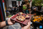 Complimentary snacks are served at a cafe on the Barkhor Street in Lhasa, southwest China`s Xizang Autonomous Region, July 5, 2024. Located at a century-old courtyard in the capital city of Xizang, this cafe with exquisite decorations is jointly operated by 28-year-old Tenzin Tegchok and his buddies. The courtyard is not only where Tenzin Tegchok was raised, but also a depot of his reminiscence. The cafe, for its part, has injected much vigor to the time-honored building that accommodates it. (Xinhua/Jigme Dorje)