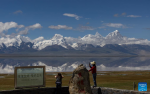 People take photos of Mount Chomolhari from a wetland park in Yadong County of Xigaze City, southwest China`s Xizang Autonomous Region, Aug. 1, 2024. (Xinhua/Jiang Fan)